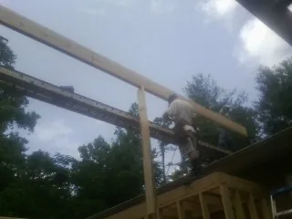 Carpenter setting a ridge beam over a new addition frame — Ice Dam Removal by Roofing Brothers in Leadore