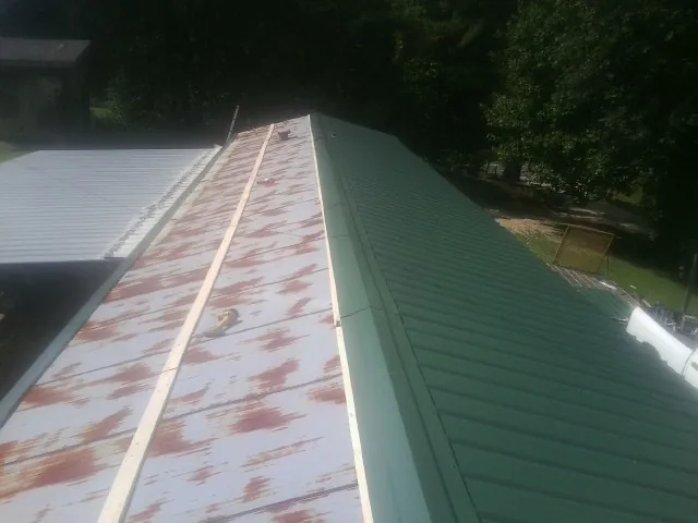 Old rusted panels beside newly installed green metal roofing — Wind Damage Roof Repair by Roofing Brothers in Leadore