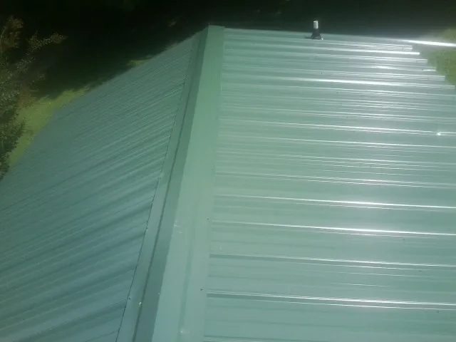 New green metal panels meeting at the ridge of a roof — Flat Roof Repair work by our crew in Leadore