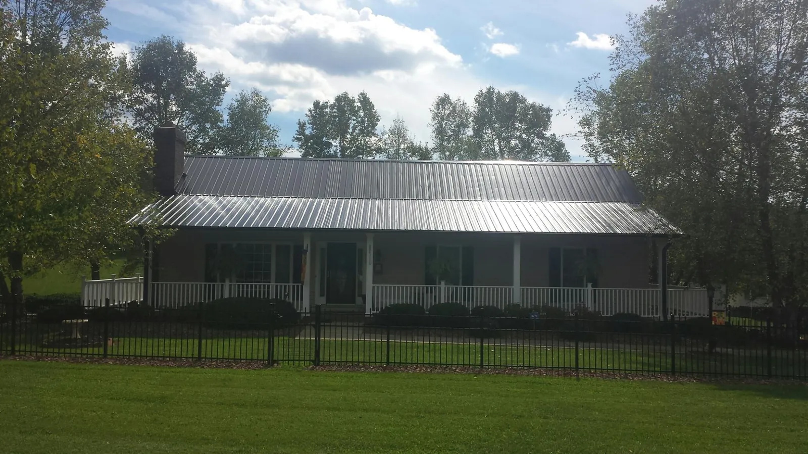 Gray metal roof on a brick ranch with a full width front porch — Gutter Guard Installation work by our crew in Leadore