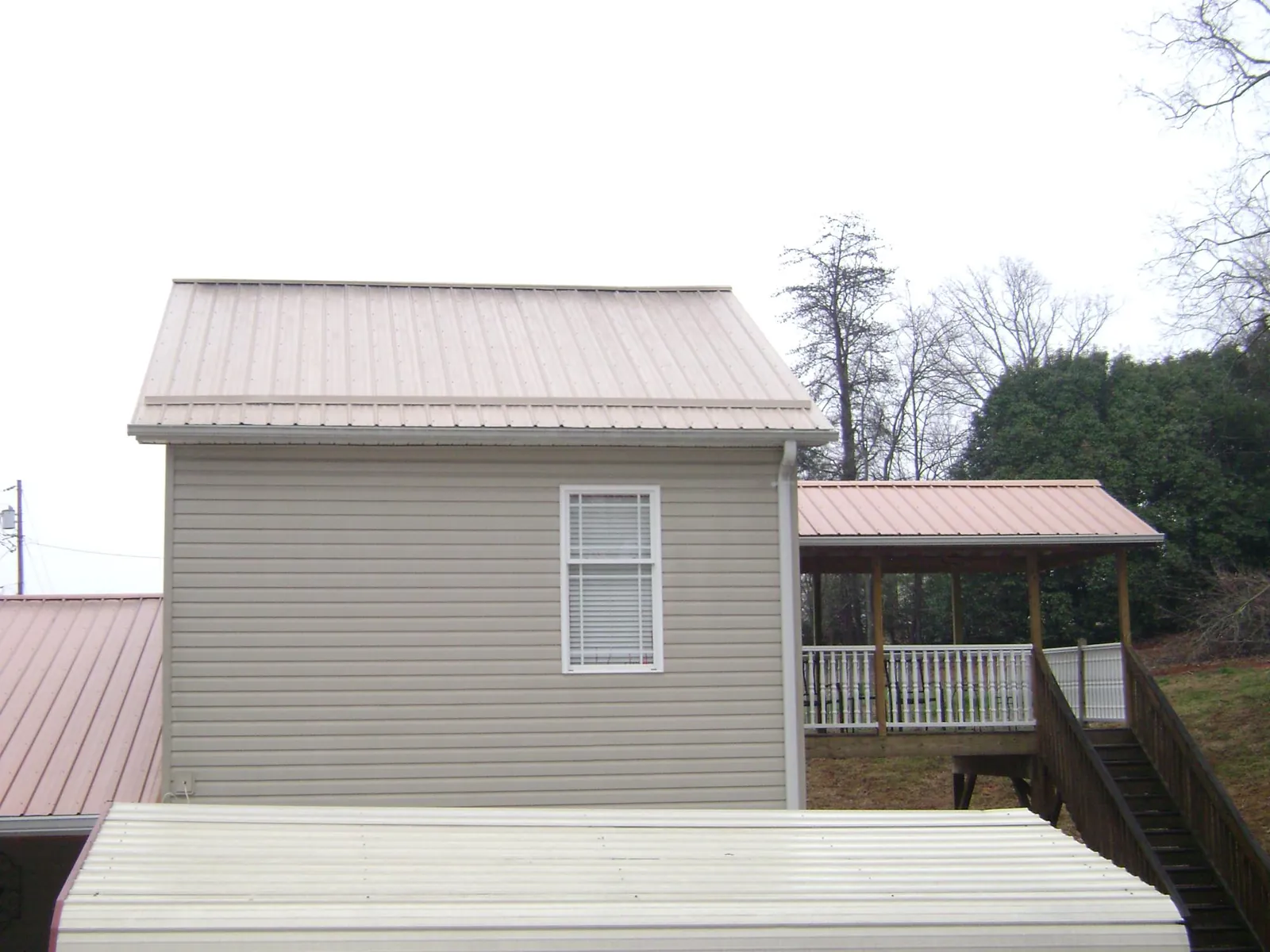 Tan metal roofs on a two story addition and attached porch, from a Roof Replacement job in Leadore