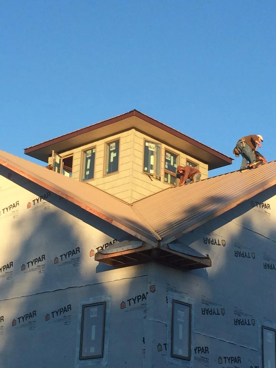 Roofers working around a rooftop cupola on a new metal roof at sunset — Roof Waterproofing in Leadore by Roofing Brothers